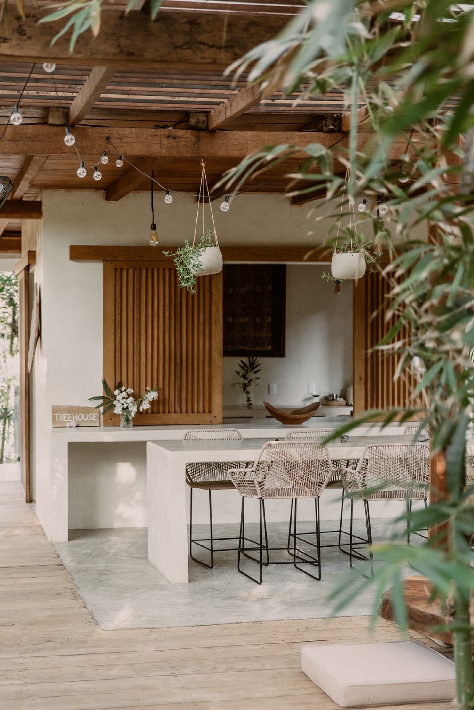 Treehouse kitchen — slatted wood, bar stools, hanging plants