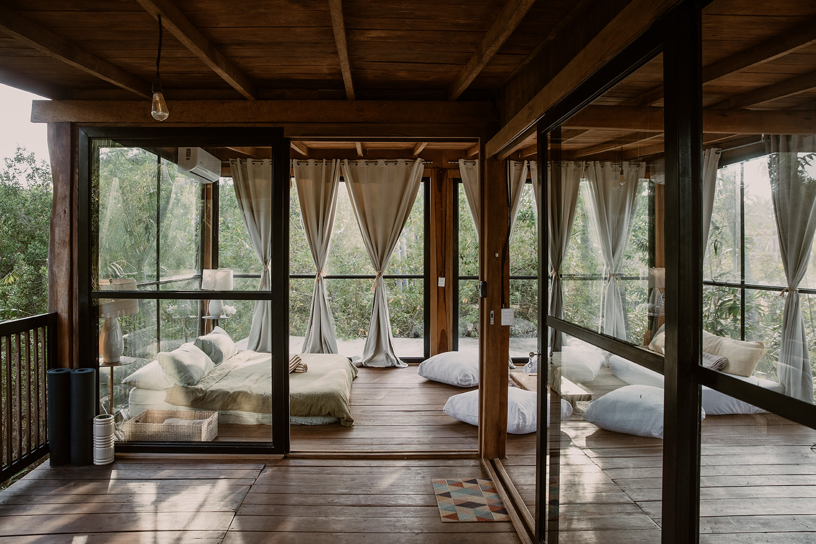 Treehouse interior — glass walls, curtains, wood and jungle