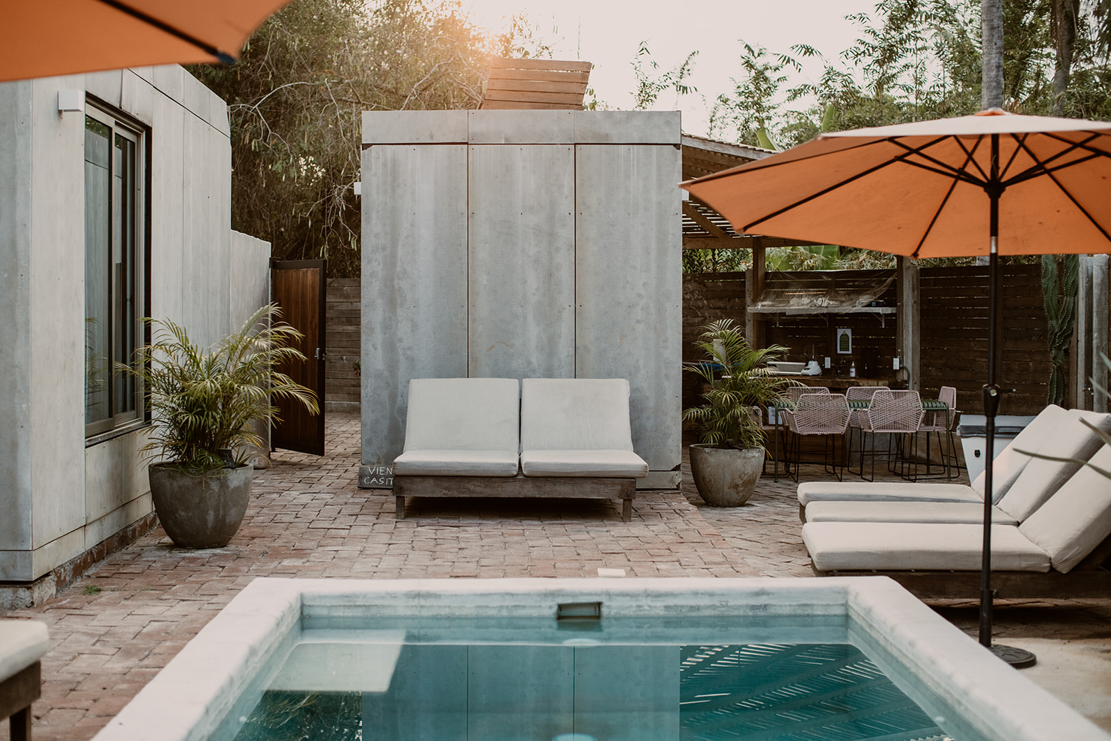 Pool courtyard with daybed, orange umbrellas, and casitas